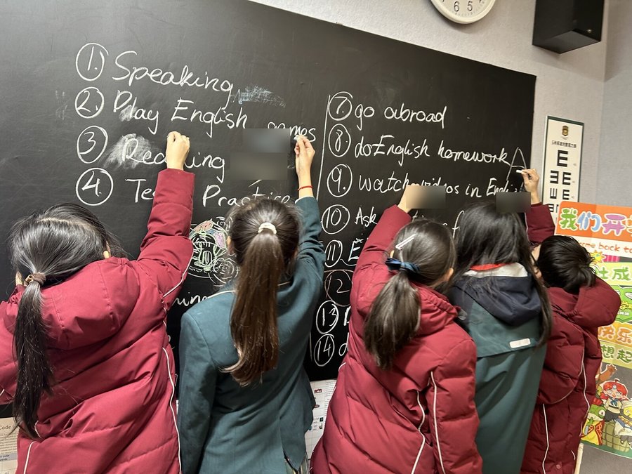 Students writing their English learning ideas on the blackboard
