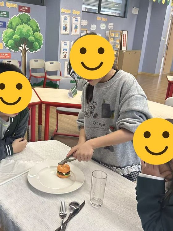 A student demonstrating how to use a knife and fork