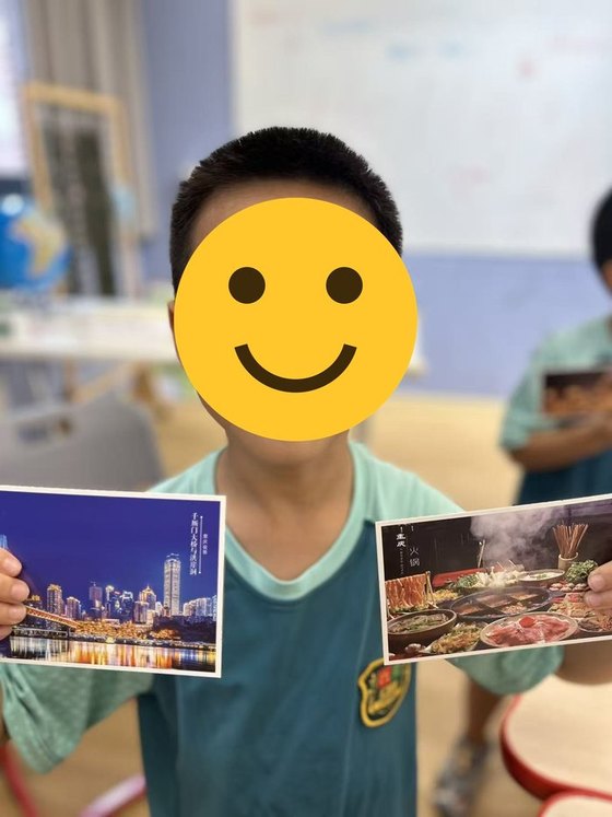 Student holding postcards of Chongqing landmarks and hot pot